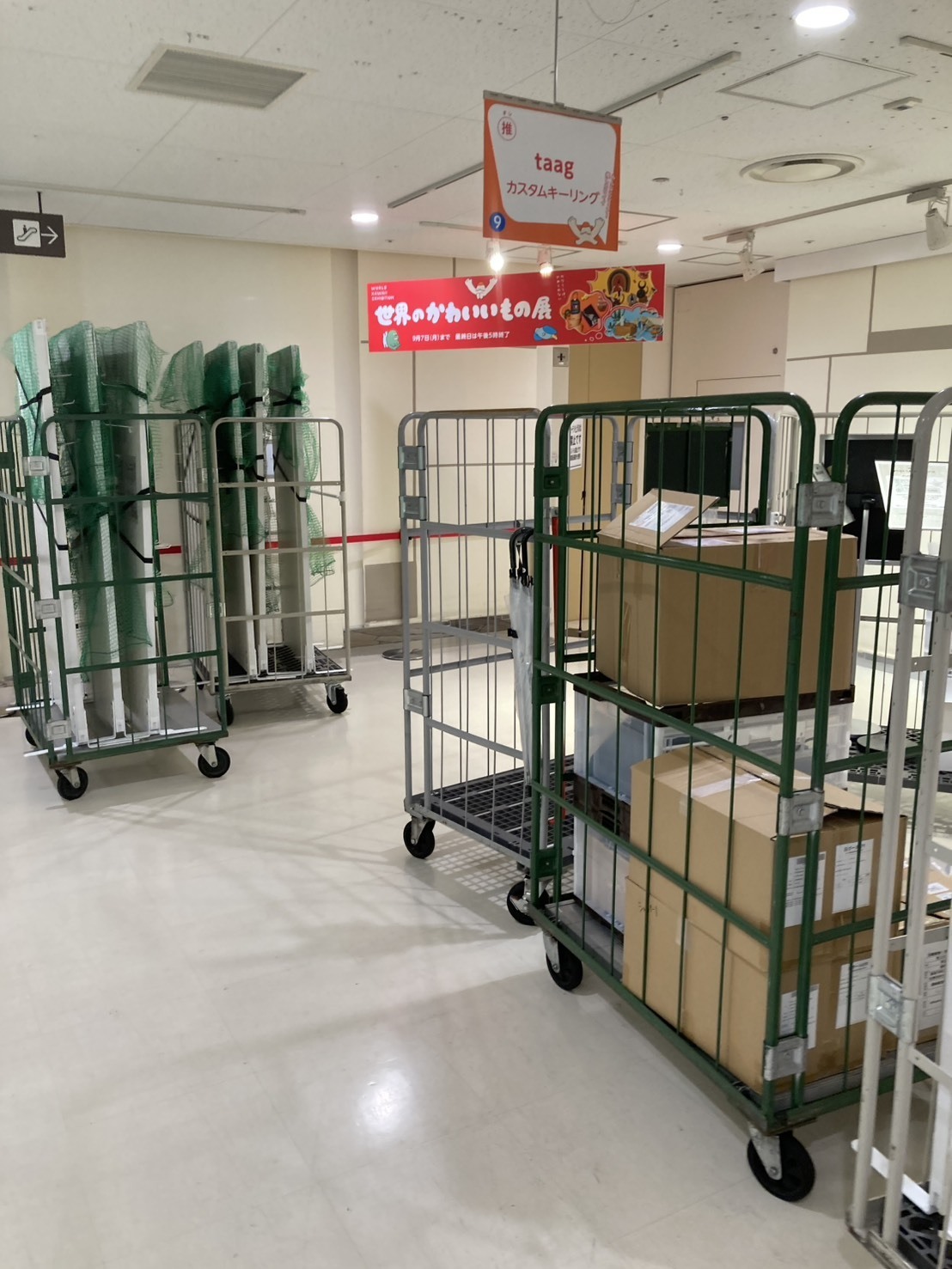 イベント会場で催事ブースの什器や荷物を台車へまとめて撤去する様子